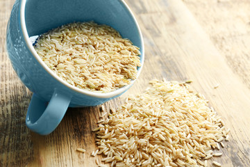Cup of long grain brown rice on table