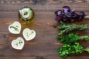 natural oil and fresh greenery for restaurant cooking on wooden kitchen table background top view