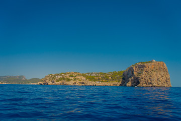 Fototapeta na wymiar Beautiful view of Mallorca balearic islands, with some buildings in the mountain in the horizon, with gorgeous blue water and a beautiful blue sky, in Spain