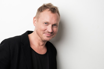 Fototapeta premium Smiling young man in black clothesstanding against white background