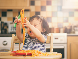 baby girl eating messy spaghetti at home