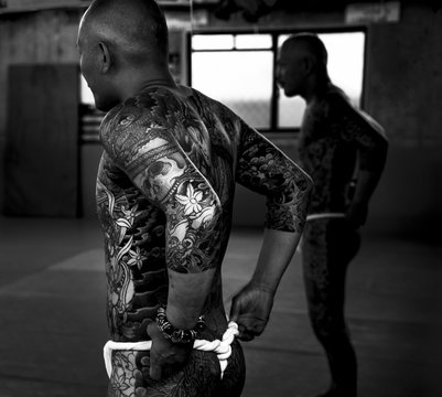Black and White portrait of a Japanese man with traditional tattoos preparing for a photo shoot