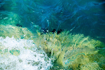  turquoise sea water crashing on calcium white stones against the azure sky on a sunny day