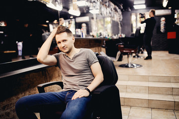Man fixes his hair in a hairdresser's barbershop.