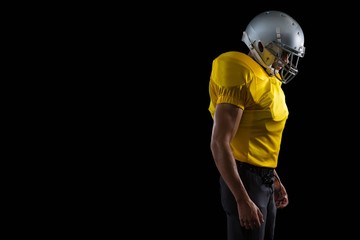 Fototapeta na wymiar American football player standing against a black background