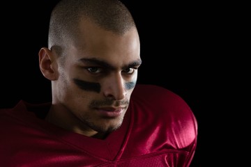 Fototapeta premium Determined American football player against a black background
