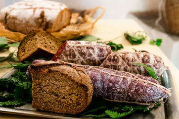 Italian salami (sausage) and wholemeal bread on a kitchen table, with other bread on the background