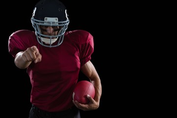 American football player pointing holding a ball in other hand