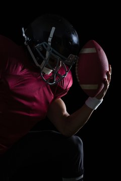 American Football Player Sitting Holding A Ball In His Hand