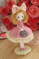 Porcelain doll on the background of a bouquet of roses