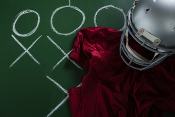 American football jersey and head gear lying on green board with