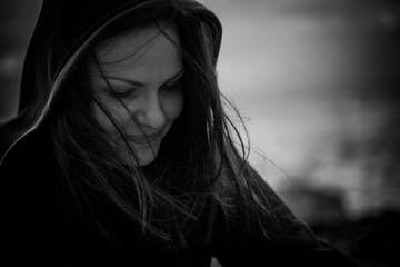 Portrait of a girl in a hood with closed eyes and smile, black and white photo