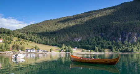 Fototapeta na wymiar Wooden rowing boat reflecting in fjord landscape