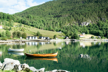 Wooden rowing boat reflecting in fjord landscape