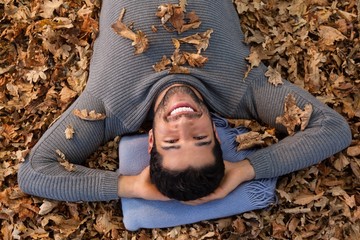 Overhead of man lying on autumn leaves