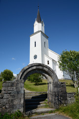 Fototapeta na wymiar White church and stone gate