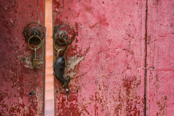 Aged wooden red door with moden and rusty vintage style fish shape padlocks