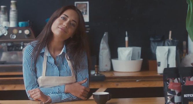 DOLLY IN Portrait of young adult female entrepreneur standing in her modern coffee roastrery, looking and smiling into camera. 4K UHD 60 FPS