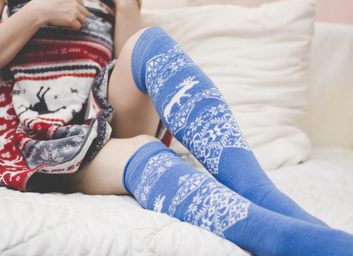 Girl legs on the bed in the Norwegian winter socks and a towel.