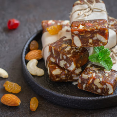 Healthy snack bars of dried fruits and nuts on black concrete ba