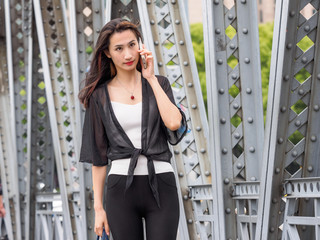 Happy adult Asian woman on the phone, with shanghai garden bridge background.