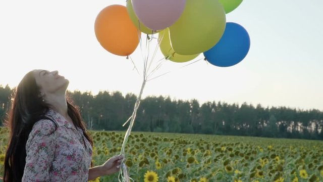 Brunette makes a selfie and enjoys colorful balloons at sunset background
