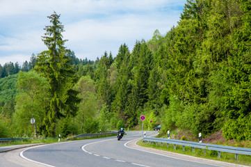 Motorcycle driver riding in the forest in Harz mountains in Germany