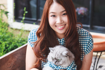 Close up of young Asian woman playing with her persian cat, human-animal relationships.
