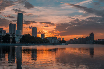 Yekaterinburg city center on sunset. City pond view, amazing clouds and sky. High buildings, skyscrapers on the embankment of the river Iset