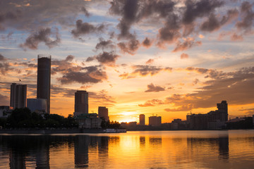 Yekaterinburg city center on sunset. City pond view, amazing clouds and sky. High buildings, skyscrapers on the embankment of the river Iset