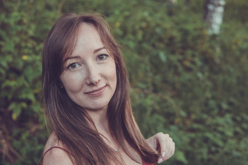 Fototapeta premium Young woman portrait in a summer forest in the mountains. Pretty girl in red dress in summertime