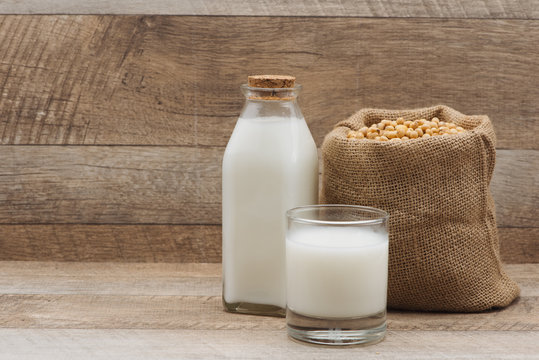 Bottle of soy milk and soybean on wooden table