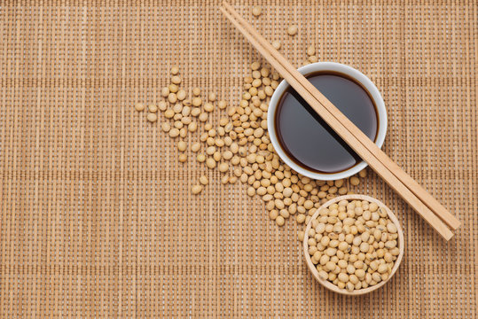 Soy sauce and soy bean with chopsticks on wooden table