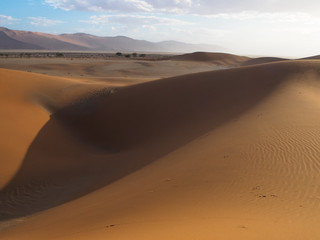 Fototapeta na wymiar Abstract shape natural rusty red sand dune and salt pan of vast desert landscape background with hot sunlight, Sossus, Namib desert