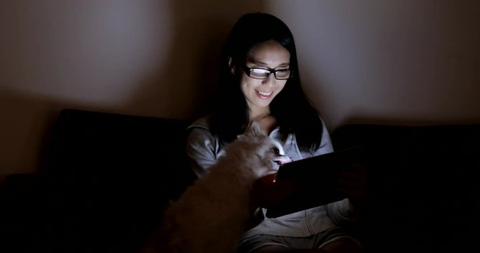 Woman looking at tablet with her dog at night