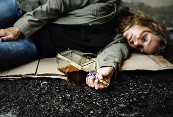 Papier Peint photo Bar Homeless woman lay down on the ground holding alcohol
