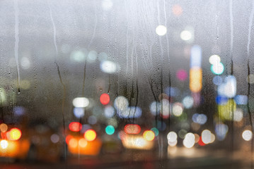 City life, road wit cars in the city trough the window during heavy rain