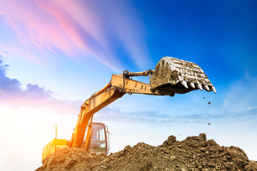 Excavator working at construction site on sunset © ABCDstock