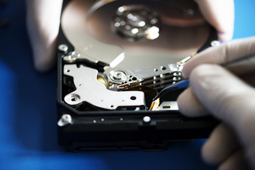Obraz premium Closeup of hands with tweezers and computer hard disk