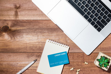 Credit card, laptop, smartphone and coffee cup on wooden table