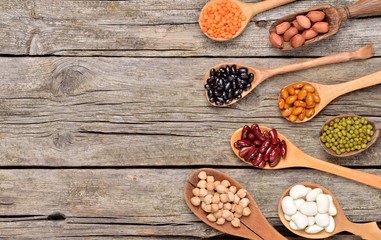 Natural grains, consisted of black bean, red bean, green bean, soybean seeds in wooden spoon on vintage style wooden background.