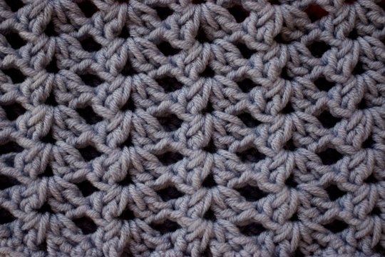 a close-up of a simple beige crochet pattern. Texture of Pink and Gray crochet yarn textile as background. Top view. Vertical direction of threads.