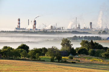 Working Nitrogen Plant in smoke in summer morning.  Abandoned village in the foreground. Grodno, Belarus.