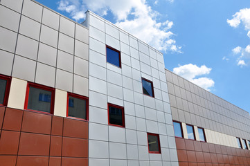 Facade of a modern building of gray and brown sandwich panels on a sunny day. Architectural background.