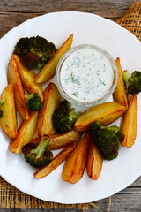 Oven roasted vegetables. Baked potatoes with broccoli and sour cream sauce. Easy and healthy vegetarian food. Vertical photo. Top view