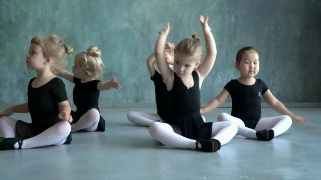 Beautiful and stately ballet teacher in the classroom teaches children ballet and corrects the girl. Warm-up before the ballet.