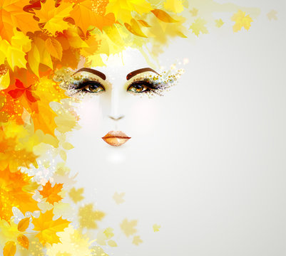 Beautiful woman face is in autumn circle of yellow and orange leaves on the light background.
