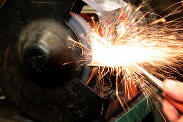 Grinding metal with an electric grinder in a workshop