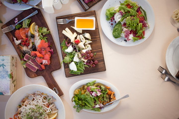 Snacks, tapas and salads on a wooden Board. Table setting in restaurant