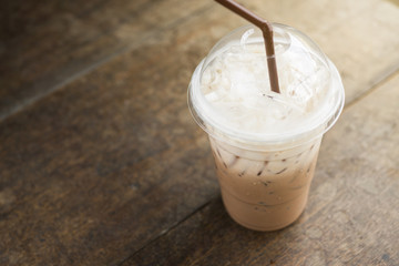 Fresh cold iced coffee drink latte in cafe on wood table background, closeup, sun light